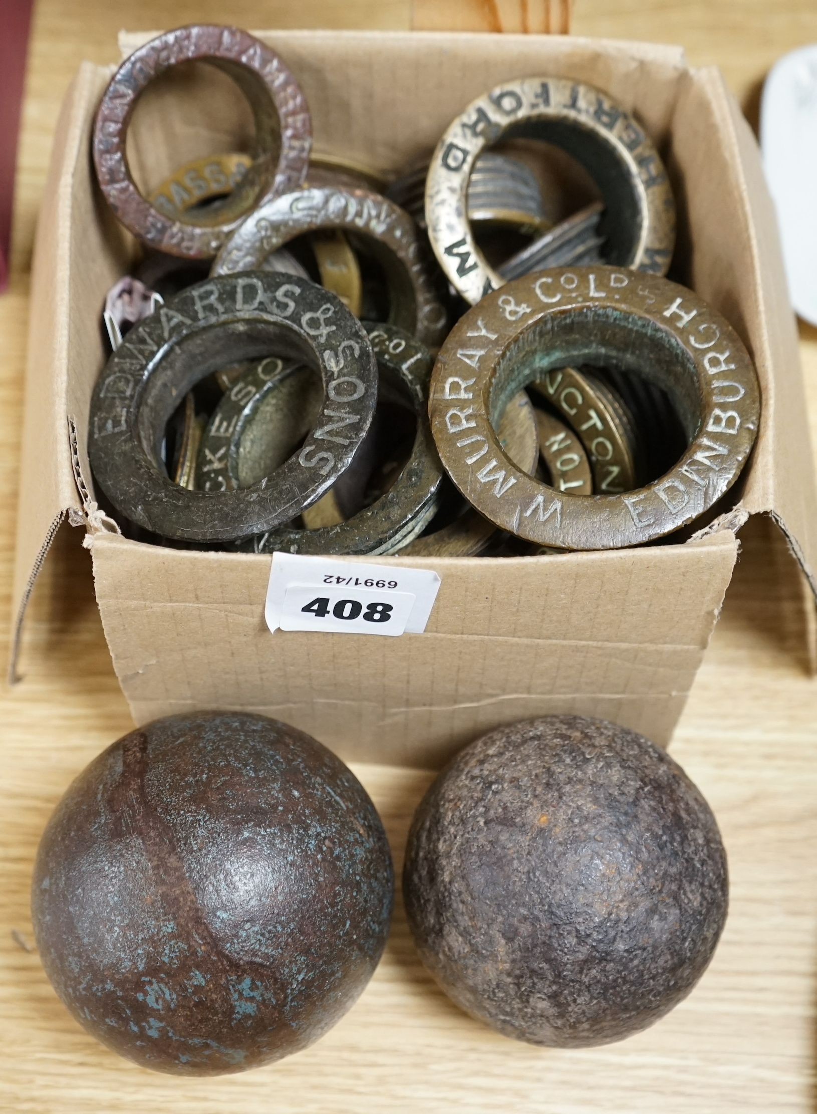 A collection of brass brewery bung collars and two cannon balls